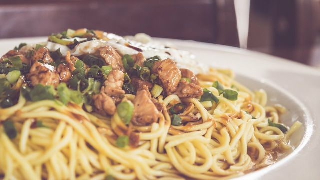 Garnish your vegan dan dan noodles with green onions and peanut flakes.